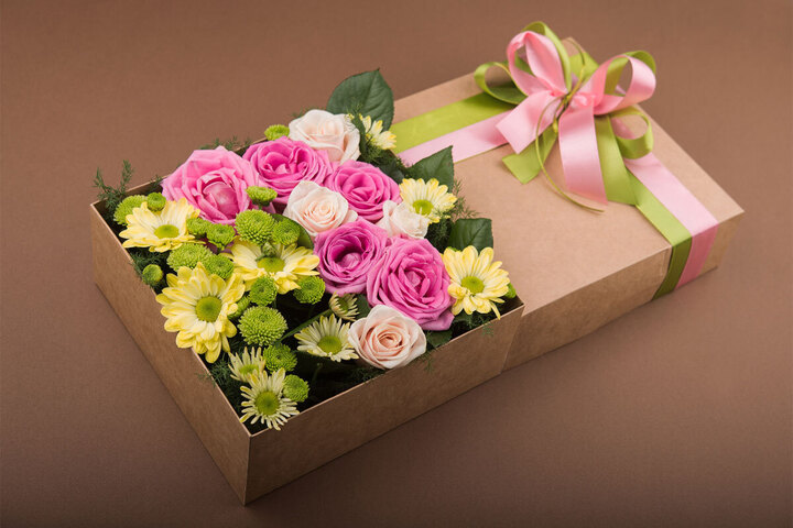 Cardboard box with pink and green ribbons and yellow and pink flowers