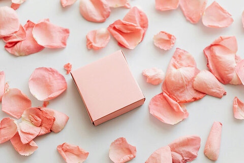 Small pink cardboard box with pink petals around it